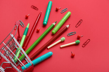 Shopping cart with different stationery on red background