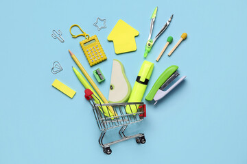 Composition with shopping cart and colorful stationery on color background
