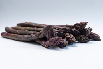 Real bunch of Purple Asparagus Plant On Gray Background, Closeup Fresh Organic Home Grown Green Vegetable, Bio Food. Horizontal plane