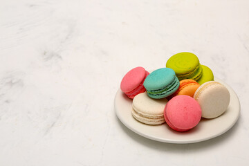 Plate with sweet macaroons on white background