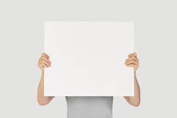 man holding blank white poster isolated on gray background. mockup, space for text