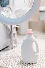 Washing gel liquid laundry detergent and fabric softener nearby washing machine, peshtemal towel in washing machine. High quality photo