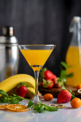 cocktail glass with fruit drink orange strawberries bananas and kumquats with mint leaves with liquid flying splash