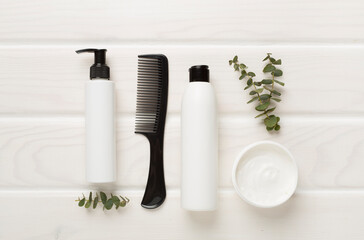 Professional hair care products with comb on wooden background, top view