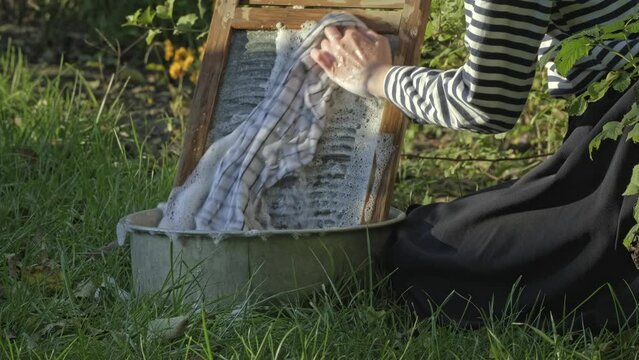 Woman washing on old retro washboard. Washing clothes the old fashion way is a way of life. Washerwoman doing laundry by hand. Antique Washboard 