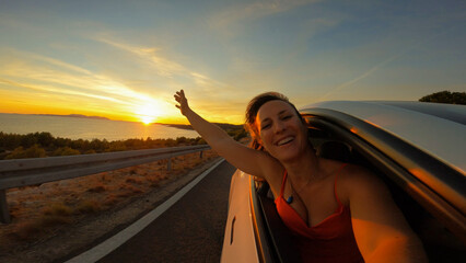 PORTRAIT, LENS FLARE: Happy lady smiles through window of a car driving by sea - obrazy, fototapety, plakaty