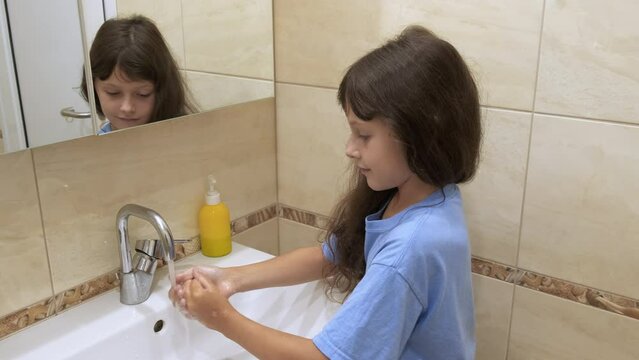 Wash hands with soap. Cute little girl in the bathroom washes her hands with soap.