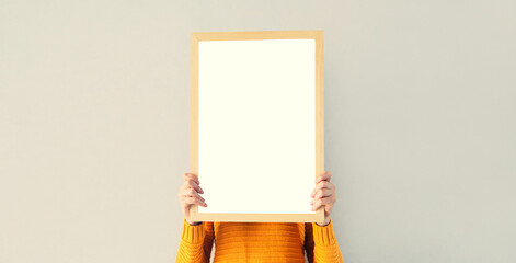 Portrait of woman showing blank a photo frame mockup on white wall in a new house