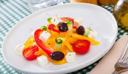 Healthy summer salad with fresh tomatoes, cucumber, bell pepper, feta cheese and olives (Greek salad) seasoned with herbs..