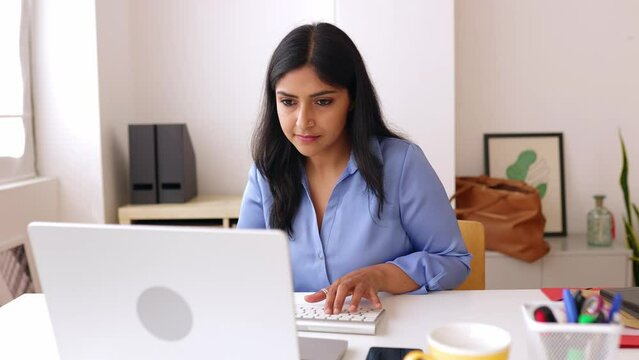Young native indian woman using laptop computer at home office. Successful female manager browsing on internet. Business and people concept.