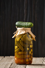 Pickled cucumbers in a jar on a dark background, copy space