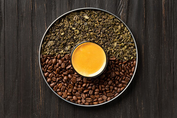 Composition of green tea, coffee beans and coffee in a cup on a dark background top view.