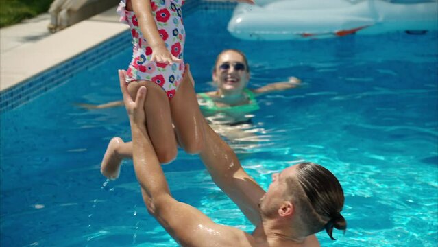 Mother with father and daughter resting and swimming in a pool in summer