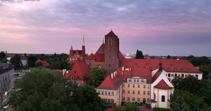 Aerial rising shot revealing Wroclaw's Ostrow Tumski district and Odra River at sunset in summer.