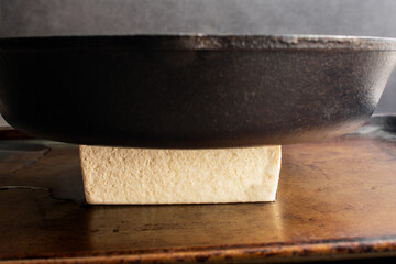 Pressing a Block of Tofu with a Cast Iron Skillet: Pressing the water out of a block of bean curd...
