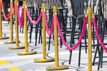 Red and yellow rope barrier in a restaurant . Street barrier of sidewalk cafe