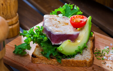 Fototapeta na wymiar Healthy sandwich with roasted tuna, avocado, lettuce leaves and tomato