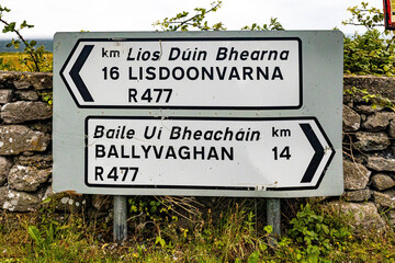 Traditional Irish road sign to Lisdoonvarna and Ballyvaghan towns written in English and Gaelic