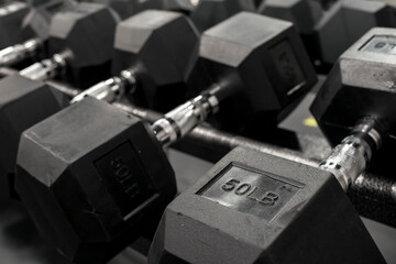 Closeup of a rack of hexagonal dumbbells at a gym or fitness club. Workout and training concept.