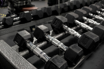 Closeup of a rack of hexagonal dumbbells at a gym or fitness club. Workout and training concept.