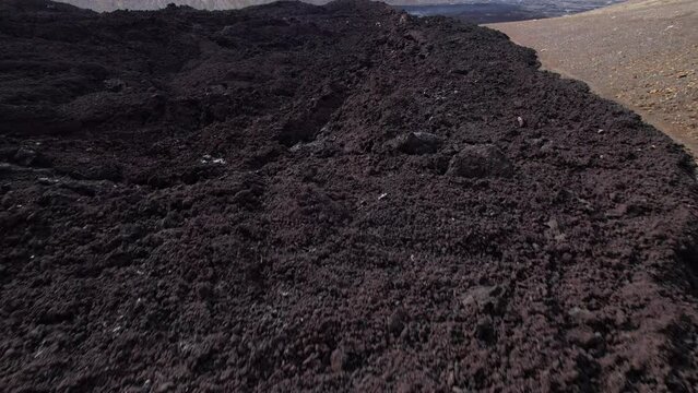 DRONE AERIAL FOOTAGE: View of cracked lava crust or ingenious rock and steam cooled down from the 2021 eruption of Fagradalsfjall volcano in Geldingadalir Valley on Reykjanes Peninsula in Iceland.