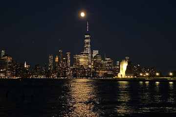 Obraz premium View of the night lights of Manhattan skyscrapers from the water, modern architecture of the New York landscape from the waterfront