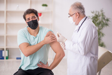 Young male patient visiting old male doctor in vaccination conce