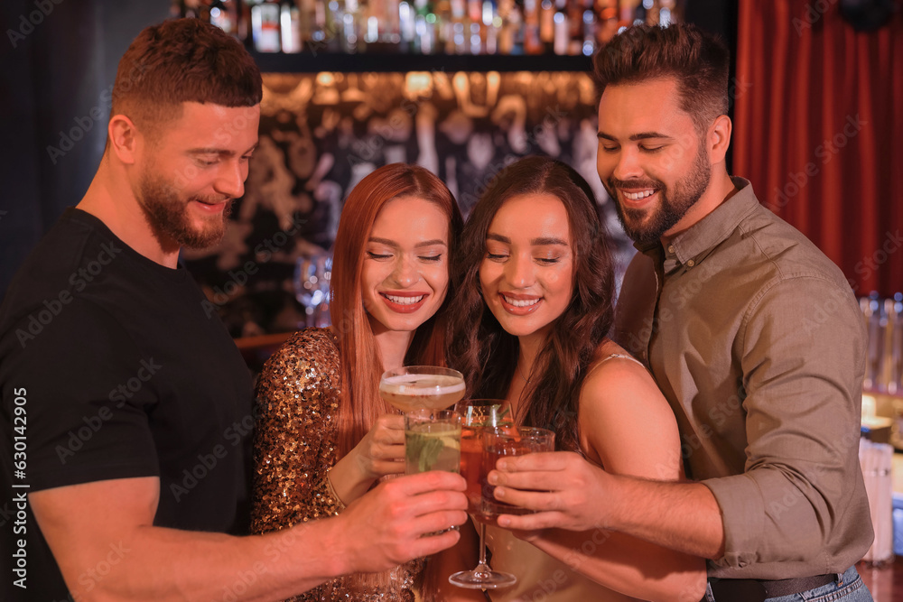 Poster Happy friends clinking glasses with fresh cocktails in bar