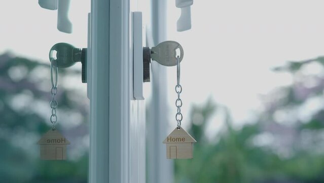 Landlord key for unlocking house is plugged into the door. Second hand house for rent and sale. keychain is blowing in the wind. mortgage for new home, buy, sell, renovate, investment, owner, estate