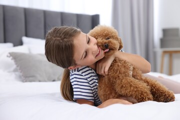 Little child hugging cute puppy on bed at home. Lovely pet