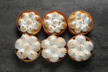 Many different tartlets with meringue on dark grey table, flat lay. Tasty dessert