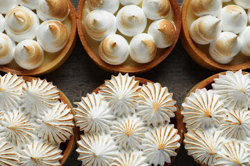 Many different tartlets with meringue on dark grey table, flat lay. Tasty dessert