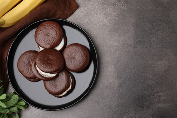 Tasty sweet choco pies, bananas and mint on brown table, flat lay. Space for text