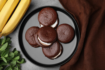 Tasty sweet choco pies, bananas and mint on brown table, flat lay
