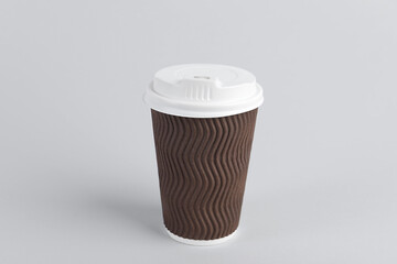 Brown paper cup with plastic lid on light background. Coffee to go