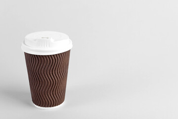 Brown paper cup with plastic lid on light background, space for text. Coffee to go