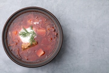 Tasty borscht with sour cream in bowl on light grey table, top view. Space for text