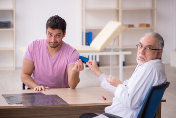 Fototapeta premium Young male patient visiting old male doctor
