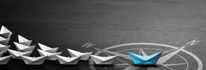 Blue Paper Boat With Compass Icon Leading A Fleet Of Small White Boats On Modern Black Wooden Table - Leadership Concept