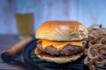 burger with bacon and cheese, with a blurred drink in the background