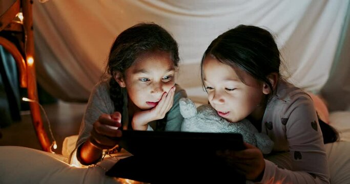 Tablet, girl children or sisters reading in a bedroom tent for storytelling or bonding together at night. Technology, family or love with female sibling kids lying on the floor in the home at bedtime