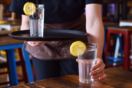 Restaurant Server Placing Glass Of Cold Water With Lemon On A Table