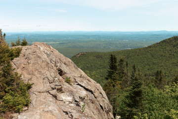 Fototapeta na wymiar vue sur le sommet d'une montagne avec un gros rocher en été avec une forêt dans la vallée