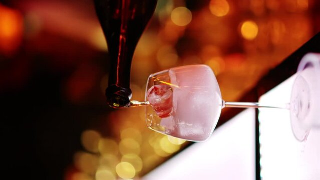Barman making cocktails with white sparkling wine at the bar at night with red neon lights, slow motion vertical screen