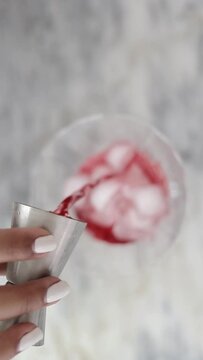 Chica verte jugo de manzana en una copa con hielo, toma desde arriba sobre la meseta de la cocina. Video formato vertical
