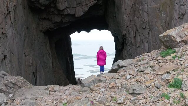 Drone reveal majestic hole through Torghatten mountain with woman in foreground