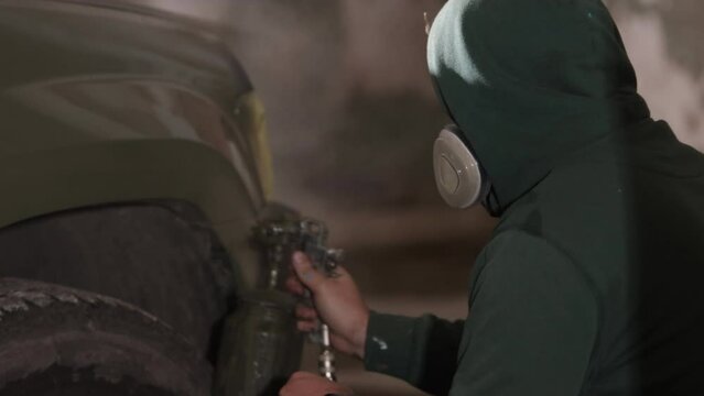 Wearing respirator, Respirator masks, Mask wearing. Respirator-equipped man employing spray gun to coat vehicle.