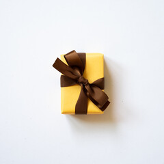 Yellow gift box and brown ribbon isolated on white background. top view, copy space