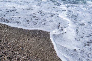 A soft wave runs on a sandy shore on a summer day. Empty space can be used as background for display or montage your top view products.