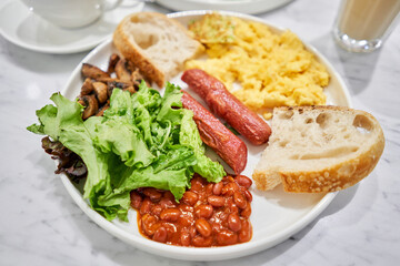 Simple American style Breakfast with sausages, scrambled eggs, baked beans, mushrooms and tomatoes. This dish is full of nutrients that you needed.